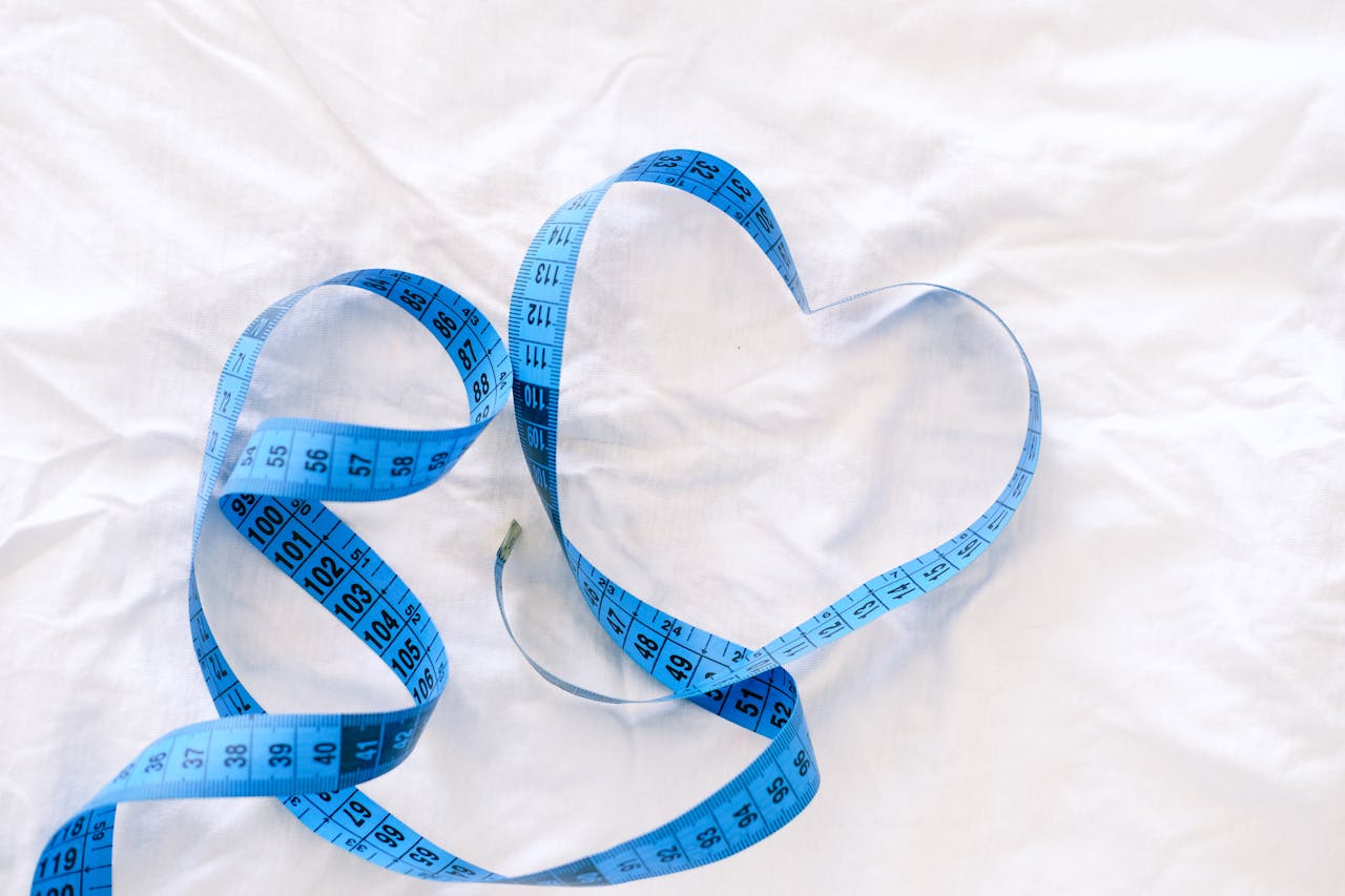 Blue measuring tape arranged in heart shapes on white fabric